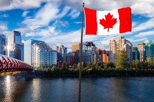 National Canadian Flag Composite. Peace Bridge across Bow River during a vibrant summer sunrise. Urban Downtown City Skyline. Taken in Calgary, Alberta, Canada.